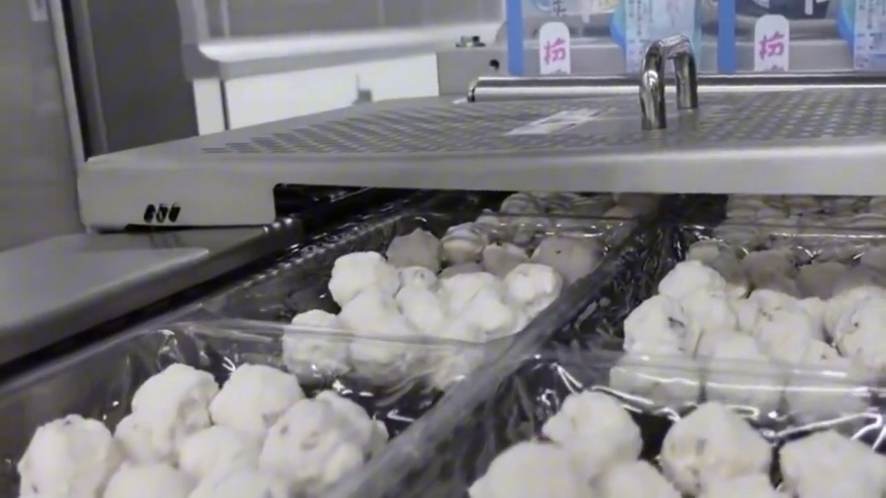 Fish balls moving through a hot-water processing stage in supplied operating footage